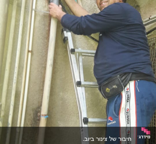 אדם על סולם מתקן צינור מים חיצוני